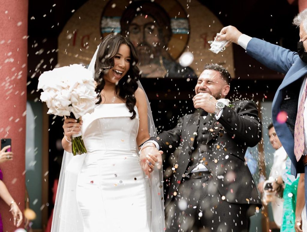 bride and groom smiling outside church with confetti throw