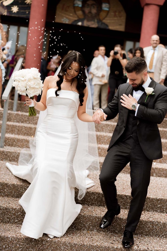 bride and groom smiling outside church with confetti throw