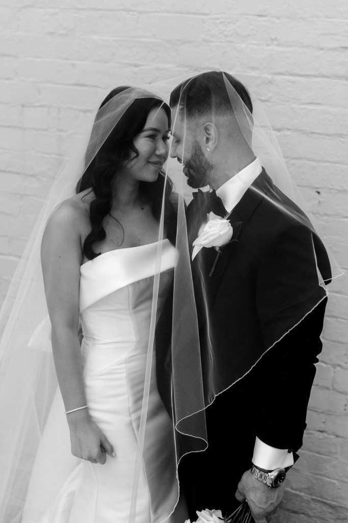 brides and groom touch heads under viel