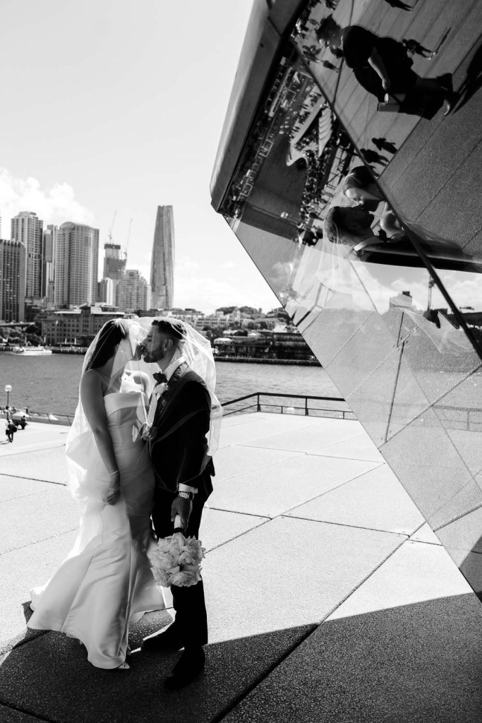 bride and groom in viel together kissing black and white