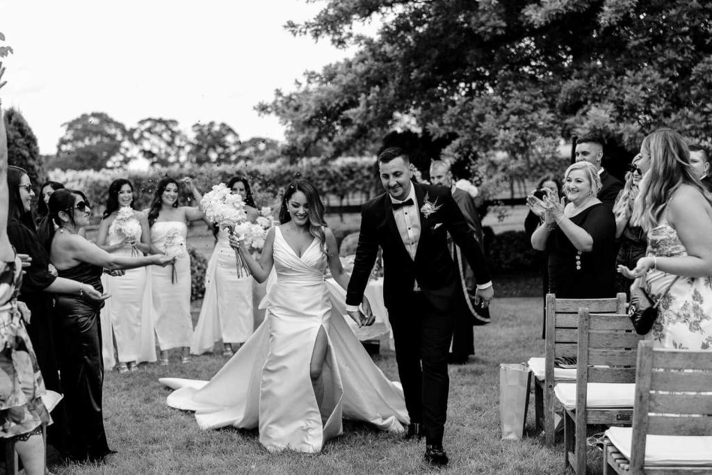 Smiling bride and groom walking down aisle