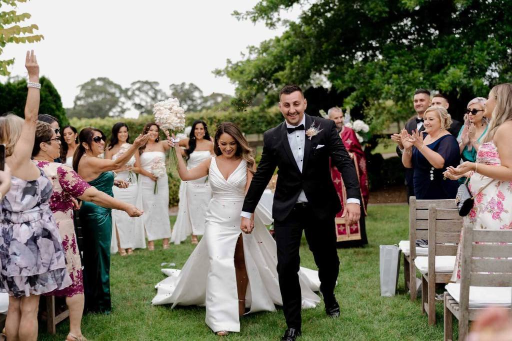 Smiling bride and groom walking down aisle