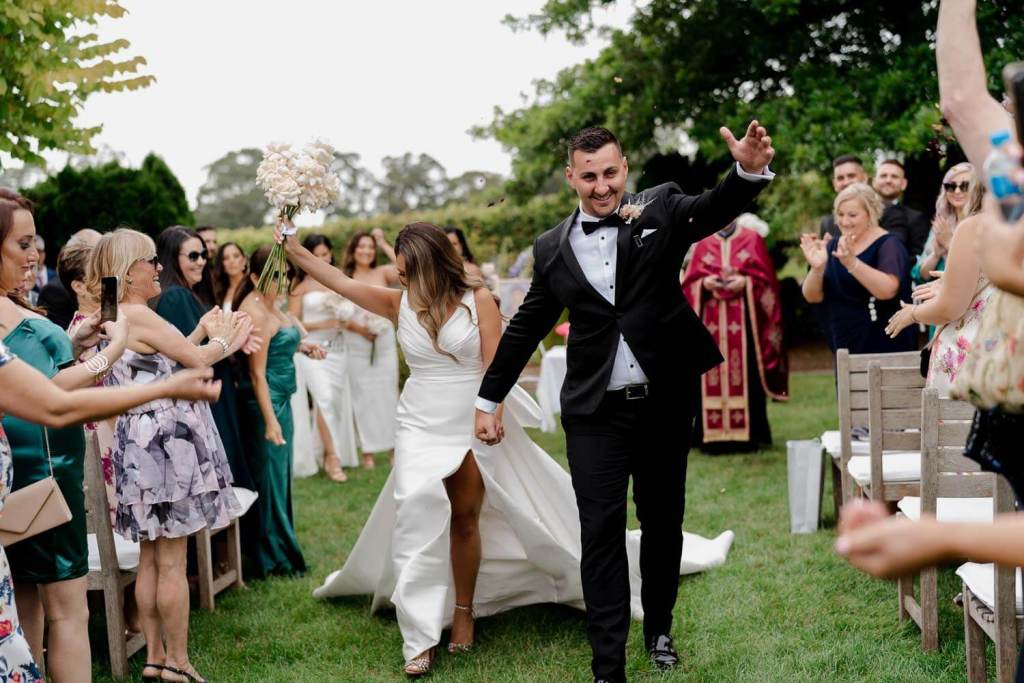 Smiling bride and groom walking down aisle