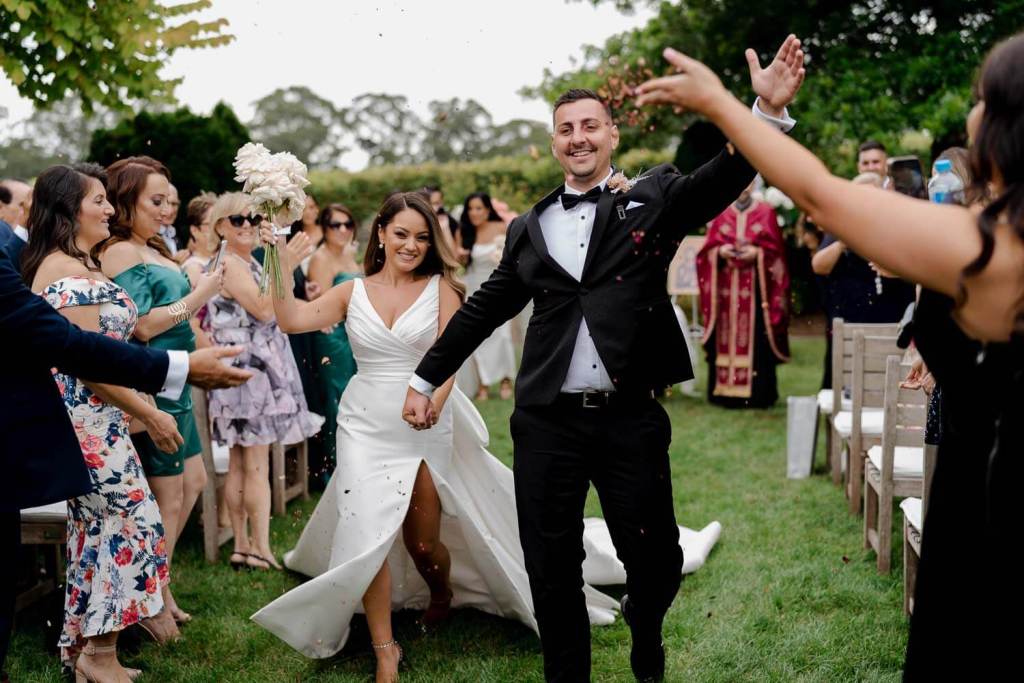 Smiling bride and groom walking down aisle