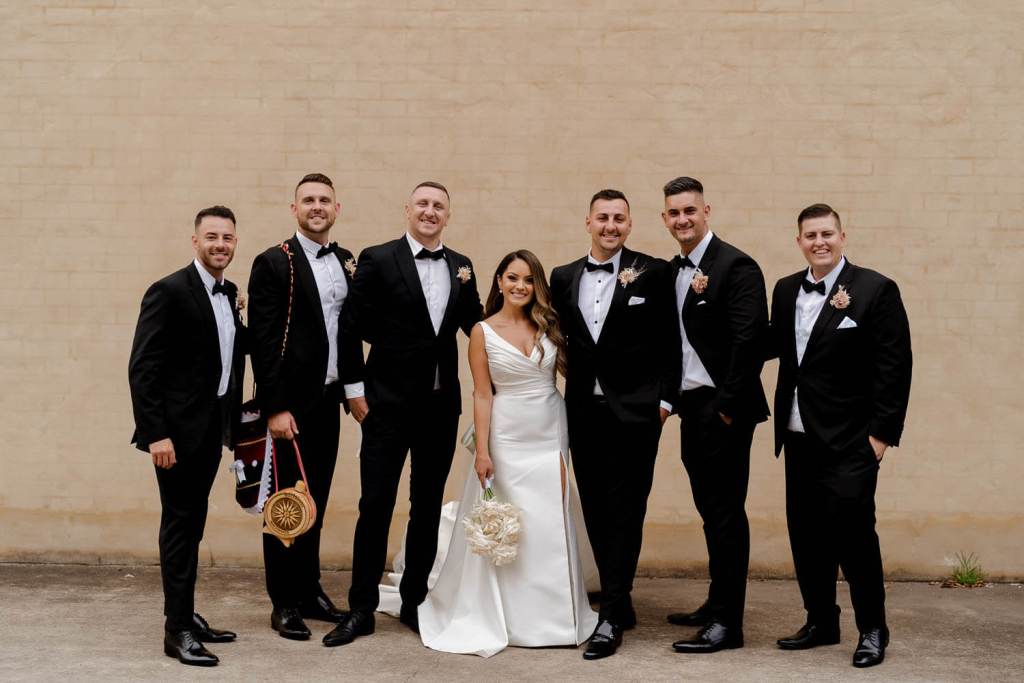 Groomsman and bride smiling on brick wall