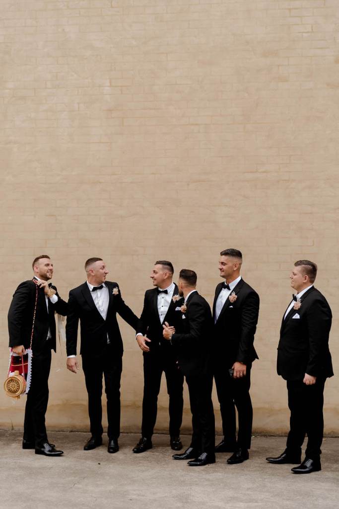 Groomsman smiling on brick wall