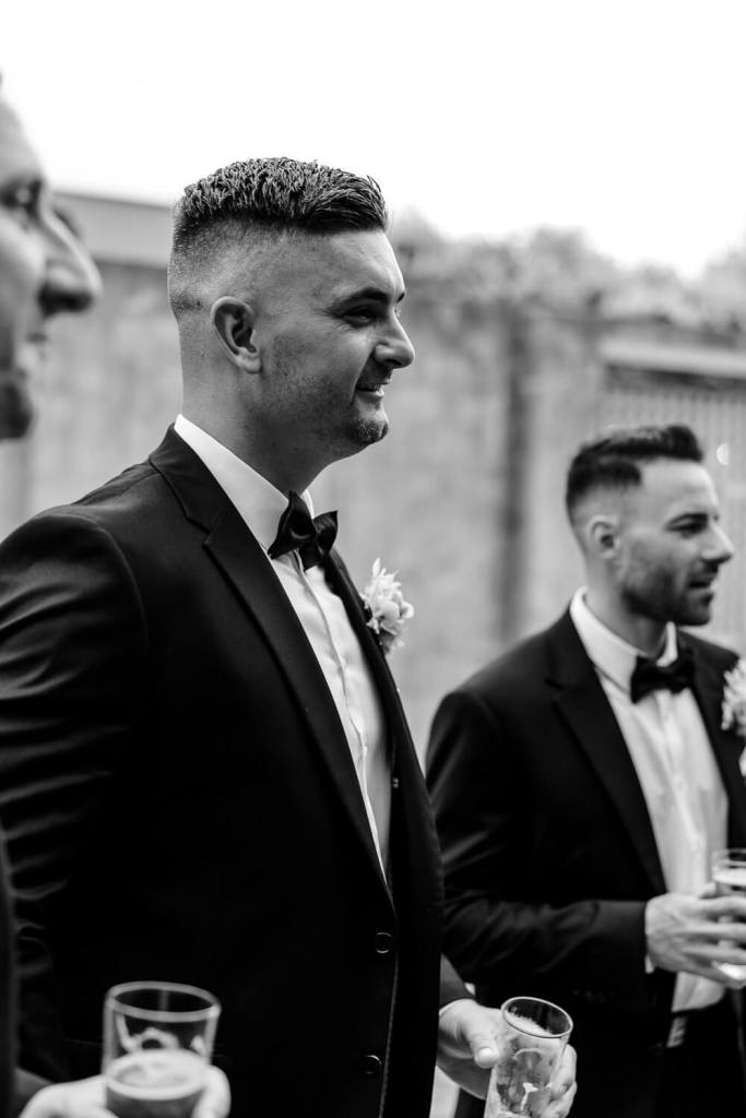 Groomsman smiling with drink