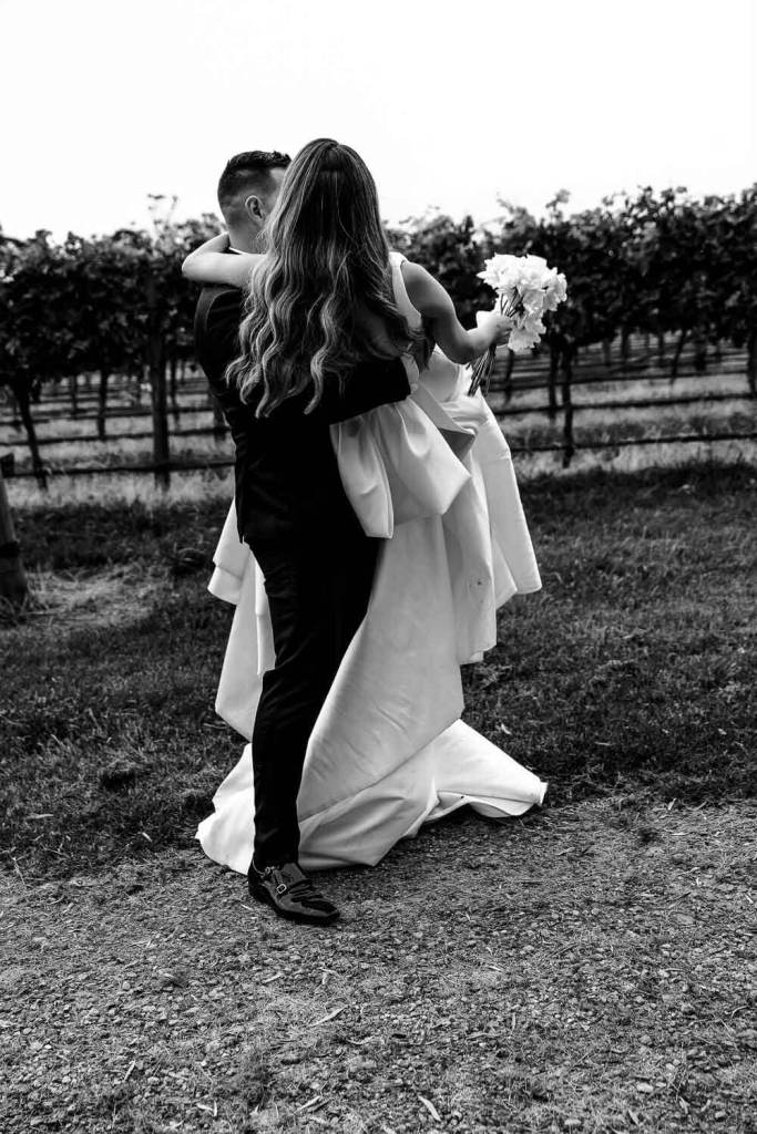 Groom lifting bride in garden