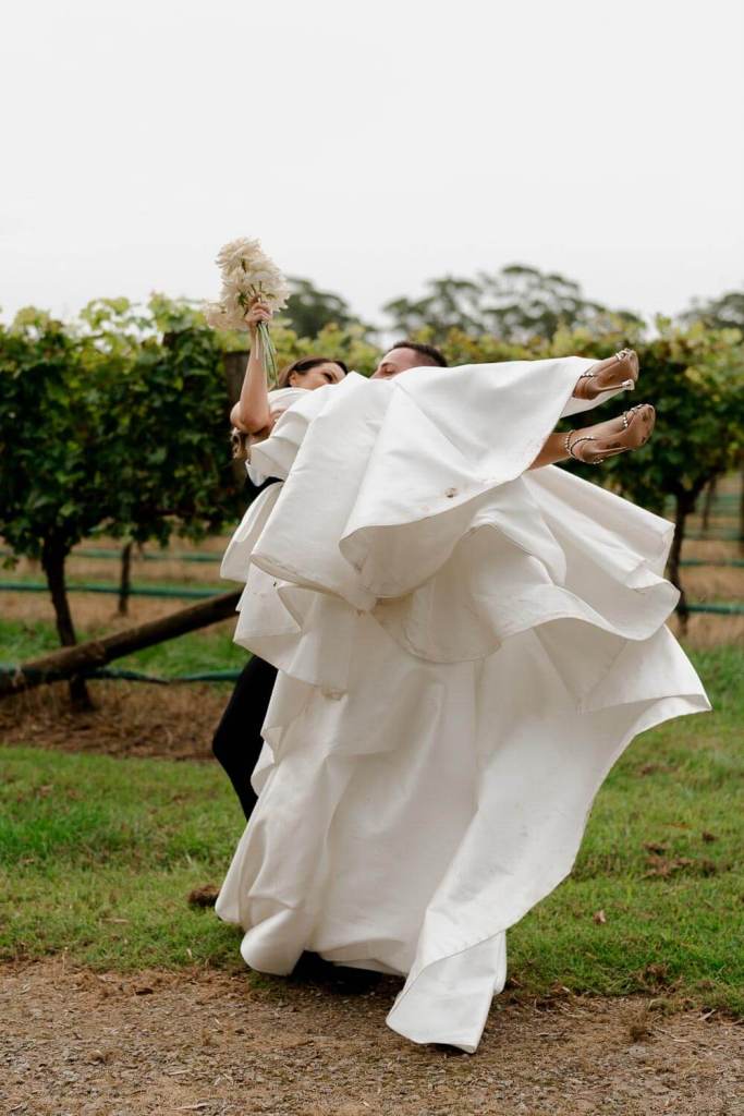 Groom lifting bride in garden