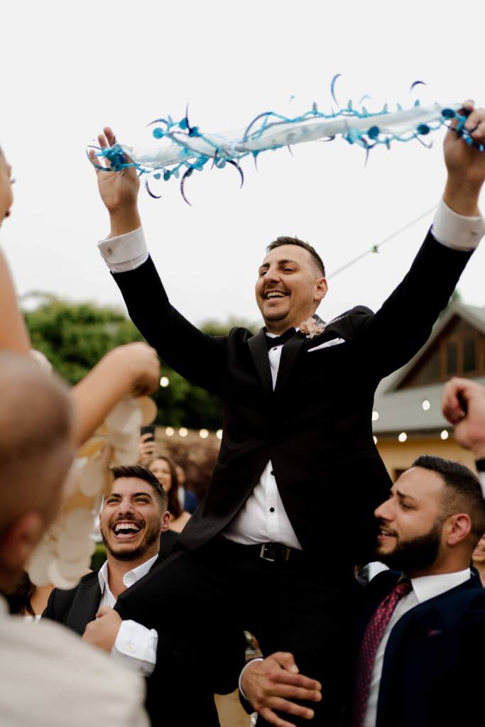 Groom on guests shoulder dancing