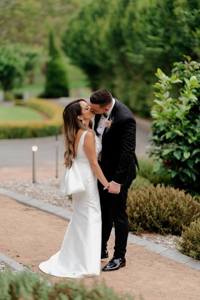 Bride and groom kissing in garden