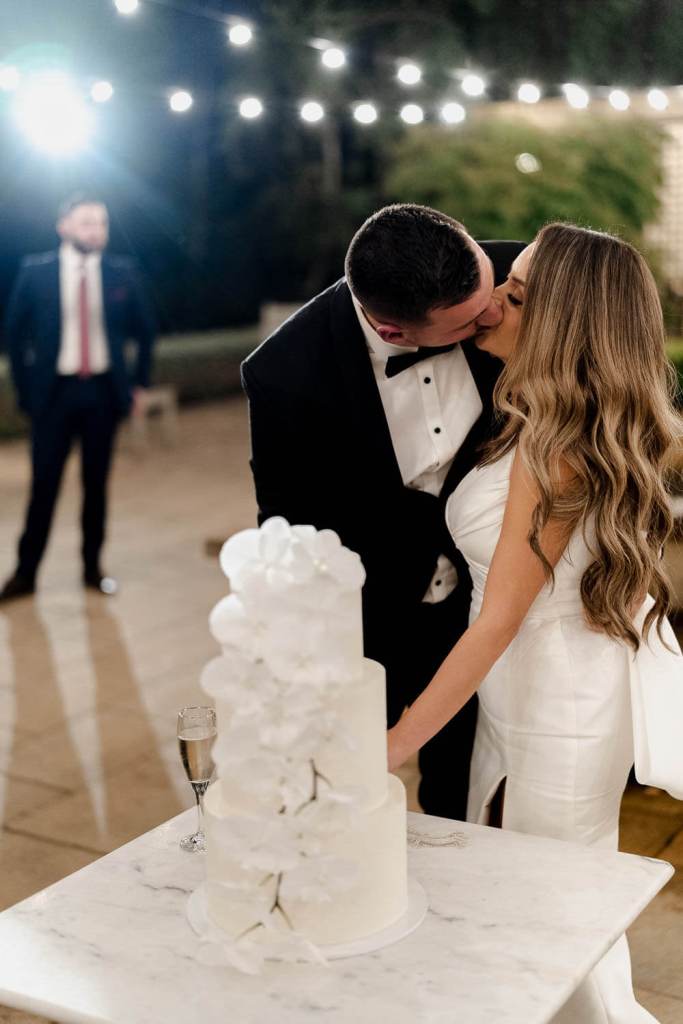 Bride and groom kissing with wedding cake