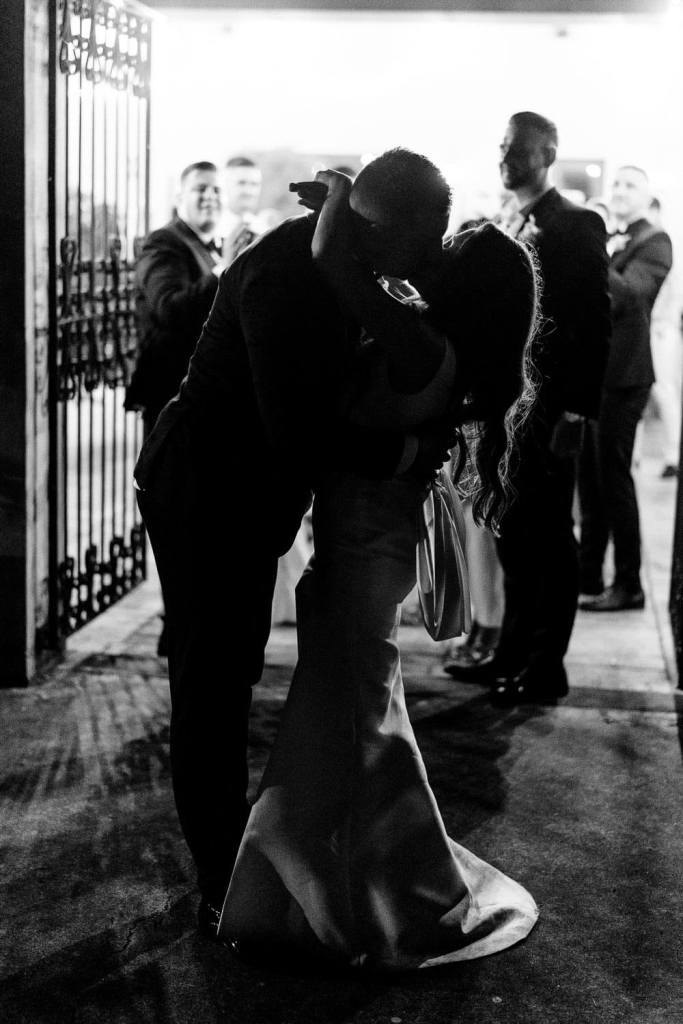 bride and groom kissing under fairy lights