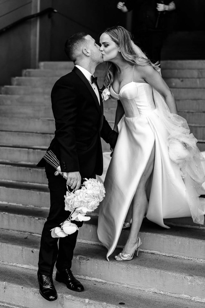 couple walk down stairs kissing black and white